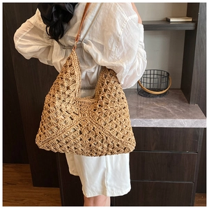 Detail of hand-woven straw tote bag with intricate patterns and brown leather straps