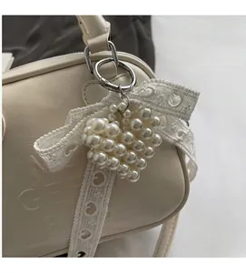 Dettaglio di un ciondolo a cuore di perle con fiocco di pizzo su una borsa in pelle