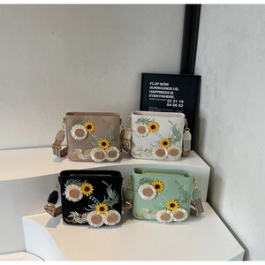 Detail of embroidered sunflower bucket bags with geometric wide strap and gold hardware