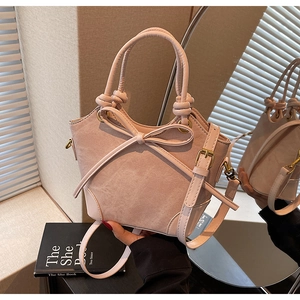 Detail view of pink bucket bag with suede finish and large decorative bow detail
