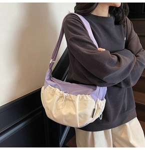Detail of purple and beige crossbody bag with drawstring design and wide strap
