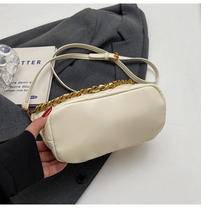 Detail of cream quilted PU leather bag featuring gold chain handle and long strap