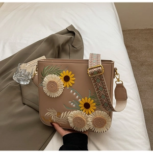 Close-up of sunflower embroidery and jacquard strap on beige bucket bag for women