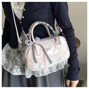 Close-up of pink Boston bag featuring delicate white lace trim and metallic bow detail
