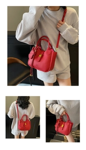 Detail of red pebbled leather handbag with gold clasp and cute dog charm attachment