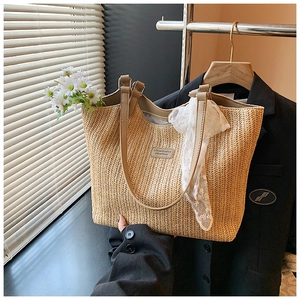 Detail of woven straw tote bag featuring PU shoulder straps and white floral lace ribbon