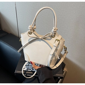 Detail of cream white leather bucket bag with bow ornament and adjustable metal buckle