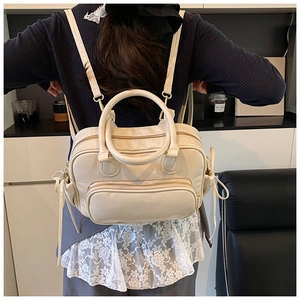 Creamy white Boston backpack with golden zippers and dual handles shown in a lifestyle setting