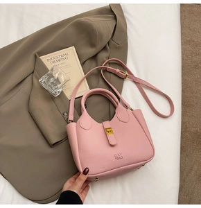 Detail of pink lychee leather handbag with gold clasp, shoulder strap and DAY BAG logo