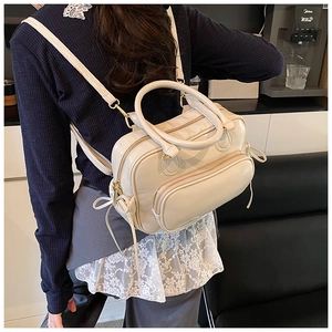 Close-up of the cream PU leather backpack with side bow detail worn by a model