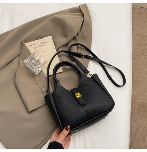 Detail of black lychee grain leather bag with gold push lock and protective base studs