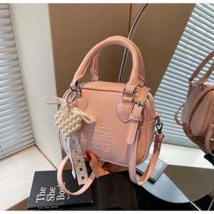 Dettaglio borsa rosa in pelle PU con goffratura a cuore e ciondolo di perle