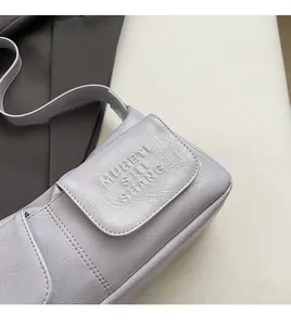 Detail of light purple pleated leather texture and embossed logo on minimalist shoulder bag