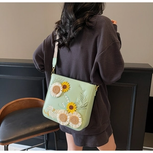 Detail of floral embroidery and geometric strap on a mint green bucket bag
