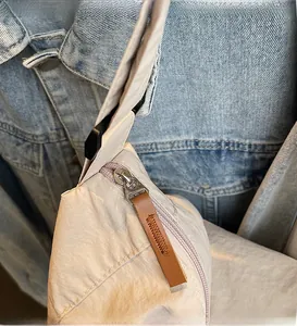 Detailed macro view of the smooth metal zipper and brown leather pull on the canvas tote bag