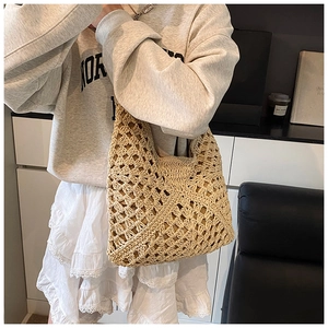 Detailed view of the hollow crochet texture on this beige straw shoulder tote bag