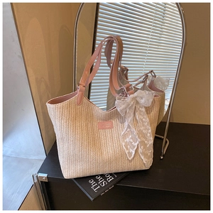 Detail of straw woven tote with pink leather handles and delicate lace bow decoration
