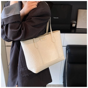 Gros plan du sac cabas beige minimaliste gaufré crocodile avec logo en métal doré