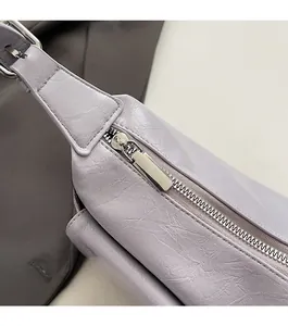 Close-up of smooth silver metal zipper and lavender leather texture on shoulder bag