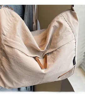 Detail of beige nylon messenger bag showing multiple zippers and brown leather pulls