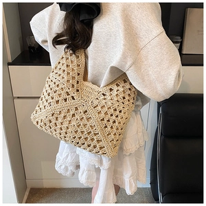Close-up of a model wearing a beige crochet straw tote bag with geometric hollow patterns