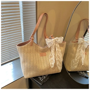 Detailed close-up of woven straw tote bag featuring pink straps and a delicate lace bow