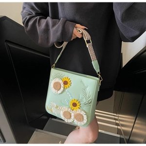 Detail of sunflower embroidery and ethnic woven strap on mint green bucket bag