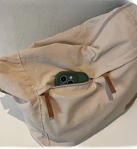 Close-up of a hidden side zipper pocket on a khaki nylon crossbody messenger bag