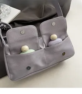 Detail of lavender textured crossbody bag showing dual front pockets and magnetic buckle
