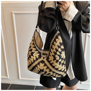 Close-up of geometric crochet texture on a straw tote bag with black leather straps