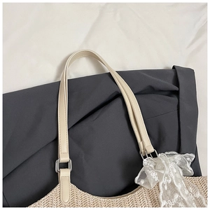 Detail of woven straw tote featuring cream leather straps and delicate lace decoration