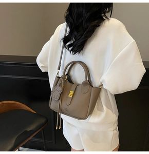 Brown leather handbag with detachable strap and dog charm shown in lifestyle setting