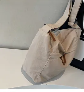 Detail view of beige crinkled nylon tote bag showing clean lines and leather zipper puller