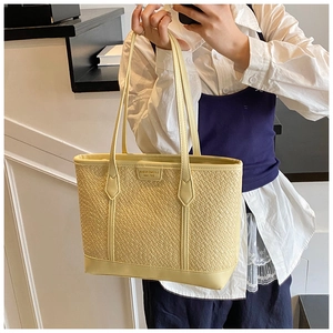 Détail de la texture tissée et des lanières en cuir de ce sac cabas jaune épuré
