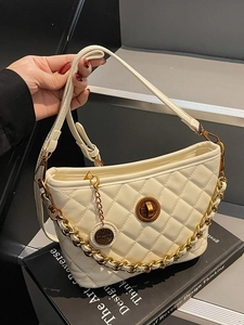 Chic beige quilted chain bag with gold hardware and flap closure on art book
