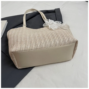 Detail of woven straw tote bag featuring cream PU leather base and lace bow accent