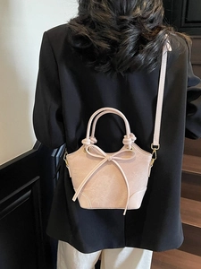 Pink crossbody bucket bag with bow detail and knotted handle shown on model
