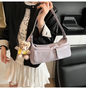 Detail of lilac PU underarm bag with magnetic flap pockets and cute teddy bear pendant