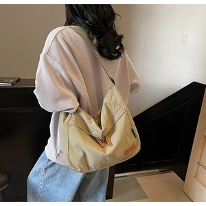 Detailed view of khaki canvas tote bag with adjustable strap and leather logo patch