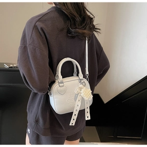 Dettaglio della borsa quadrata azzurra con finiture a cuore e ciondolo di perle chic