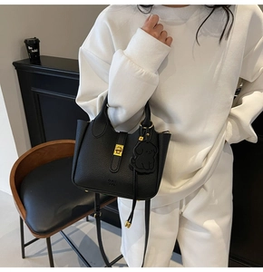 Detail of black lychee leather tote bag with gold hardware and tassel charm