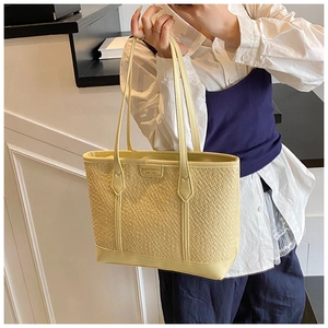 Détail du sac cabas beige tressé avec écusson en cuir et fines anses doubles stylées