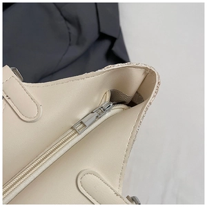 Close-up of woven tote bag showing silver zipper closure and herringbone lining detail