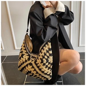 Detail of hand-woven straw shoulder bag featuring a black and beige checkerboard pattern