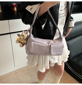 Detail of lavender pleated underarm bag with front flap pockets and plush bear charm