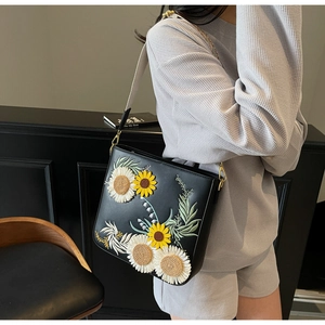 Detailed view of 3D sunflower embroidery on a black faux leather crossbody bucket bag