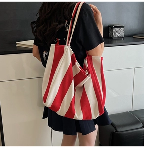 Red and white striped canvas tote bag styled on model for casual everyday look
