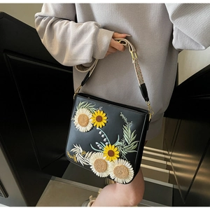 Detail of sunflower and daisy embroidery on black leather crossbody bucket bag