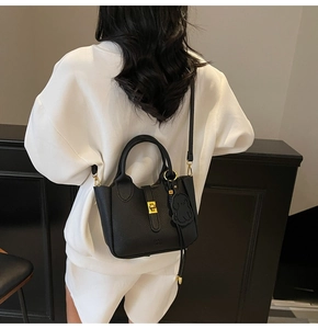 Detail of black pebbled leather tote with gold twist lock and dog-shaped charm