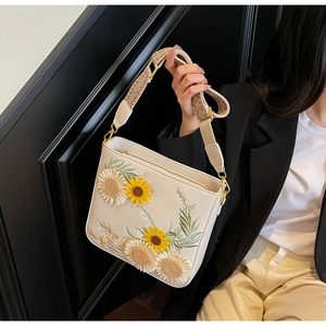 Detail of floral embroidery on off-white bucket bag with wide jacquard strap